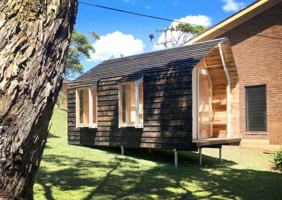 a small wooden house with a tree in the back