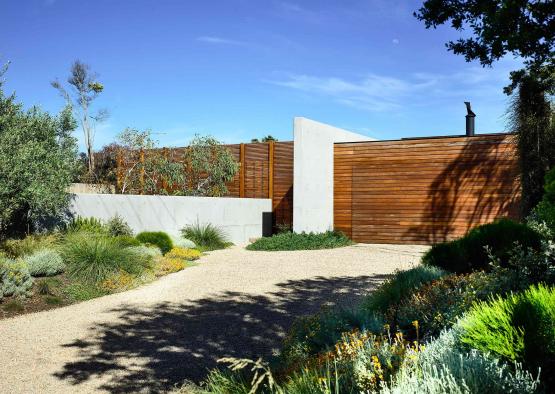 a driveway with a wood gate and a gravel path