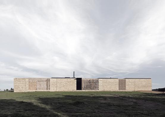 a long brick wall with a grassy field and a blue sky