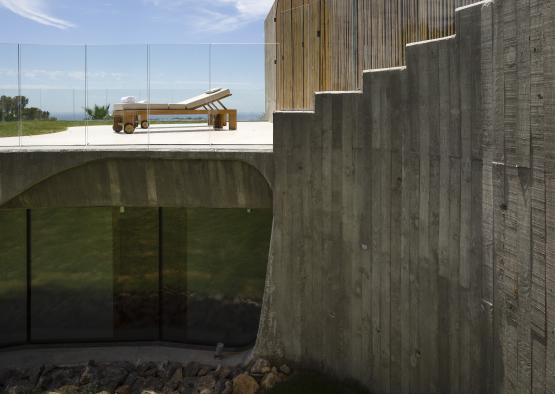 a concrete building with a glass wall and a deck chair