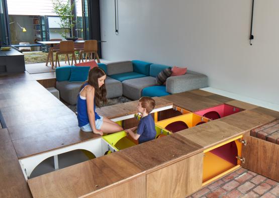 a girl and boy sitting on a table with colorful drawers