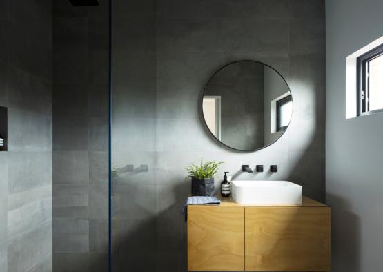 a bathroom with a round mirror and a sink