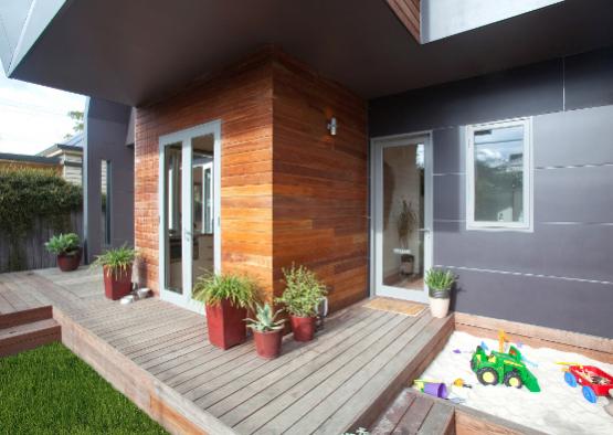 a wooden deck with a sandbox and potted plants