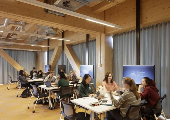 a group of people sitting at tables in a room with computers