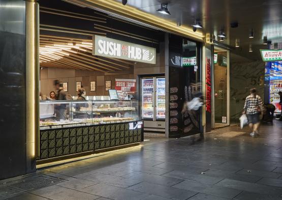 a storefront with a sign and people walking in the background