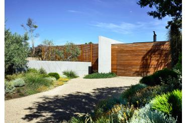 a driveway with a wood gate and a gravel path