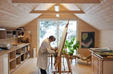 a man painting on a canvas in a room with a large window