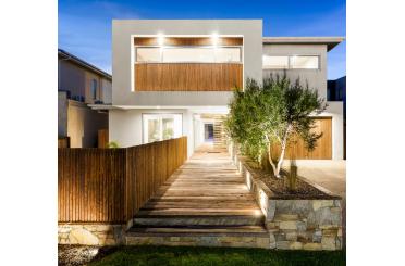 a house with a wooden walkway and a tree