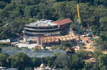 a building under construction with trees and a crane